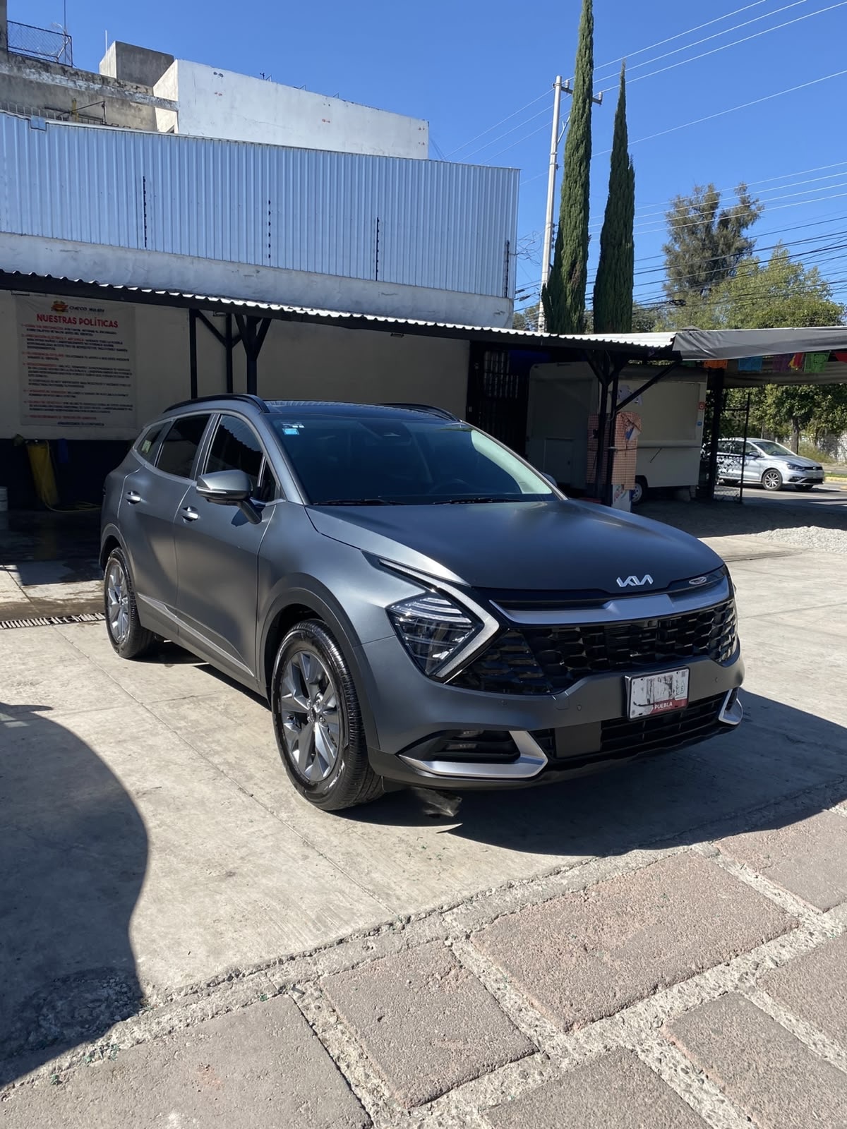 Kia Sportage gris mate estacionado frente a las instalaciones de Checo Wash